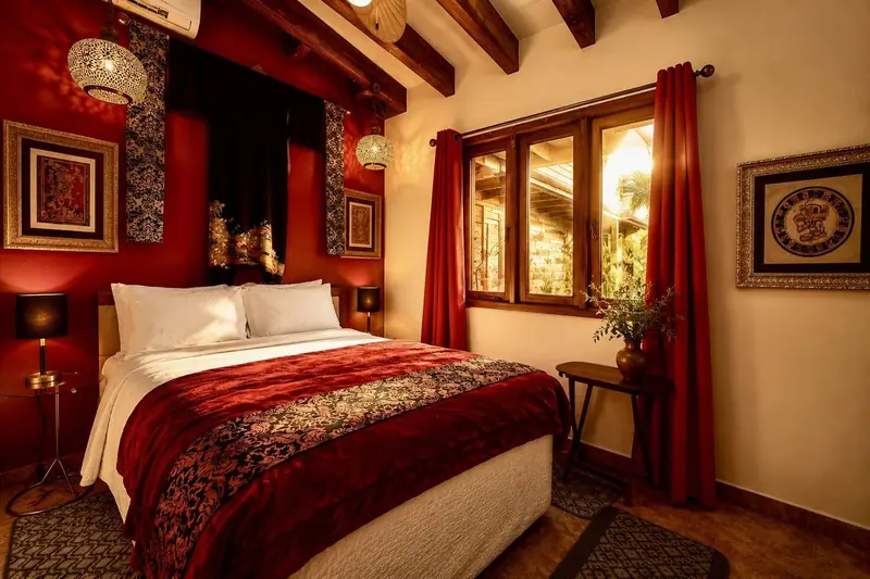 A guest room at House of Mosaic, red walls, carved beams and mosaic frames